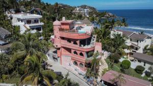 萨尤利塔Nomada Wellness Hotel的靠近大海的粉红色建筑的空中景观