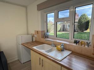 a kitchen with a sink and two windows at North Approach Harry Potter Studio Tour in Leavesden Green