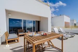 a patio with a wooden table and chairs on a balcony at Ericeira Panoramic Sea View Apartments in Ericeira