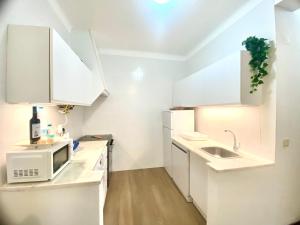 a white kitchen with a sink and a microwave at Ericeira Panoramic Sea View Apartments in Ericeira