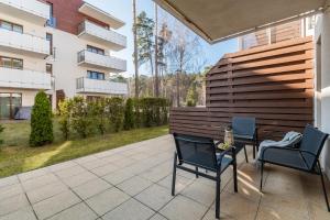 a patio with two chairs and a table in front of a building at Apartamenty Mierzeja - Baltic Park Stegna, Studio 24 m2, 500 m od plaży, bezpłatny Meleks in Stegna