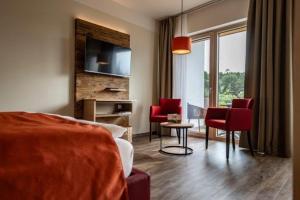 a bedroom with red chairs and a living room at Triad Gästehaus DZ in Krumbach Markt