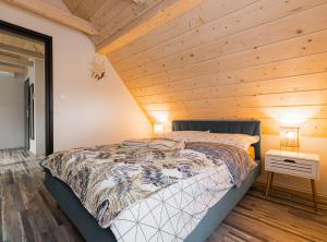 a bed in a room with a wooden ceiling at Słoneczna Wetlina - Apartament 3 in Wetlina