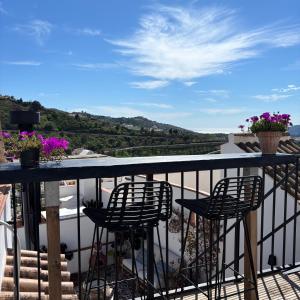 a balcony with two chairs and a table with a view at Casa Maroma in Cómpeta