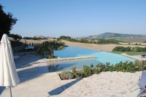 una sombrilla blanca y una piscina con vistas en Pool Villa Volterra by Villaflair, en Volterra