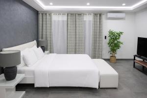 a white bedroom with a white bed and a tv at Atlas Royale Marrakech in Marrakesh