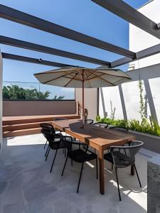 a wooden table and chairs with an umbrella on a patio at Glória Del Art - Vista, Estilo e Praticidade no Centro do Rio in Rio de Janeiro
