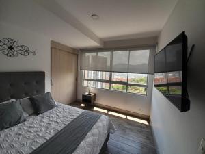 a bedroom with a bed and a large window at Amplio apartamento con vista campestre in Sabaneta