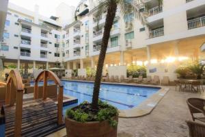 a palm tree in a pot next to a swimming pool at Bombinhas Summer Beach Apto moderno a 300 m da praia in Bombinhas