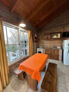 a kitchen with a table with an orange blanket on it at Cabañas Buena Vista in Sierra de la Ventana