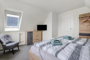 a bedroom with a bed and a chair and a television at Ferienhaus Pfanne in Hennstedt