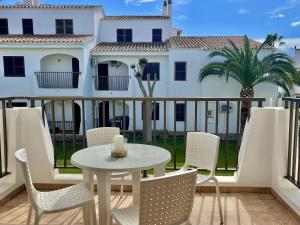 a table and chairs on a balcony with a house at Oasis Calan Porter con piscinas y junto la playa in Cala'n Porter