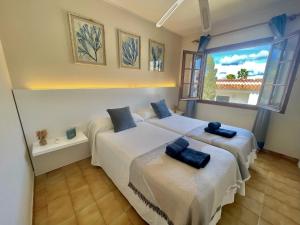 a bedroom with two beds with towels on them at Oasis Calan Porter con piscinas y junto la playa in Cala'n Porter