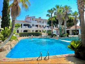 a large pool with palm trees and a house at Oasis Calan Porter con piscinas y junto la playa in Cala'n Porter +29 photos