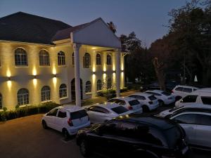 eine Gruppe von Autos, die vor einem Gebäude geparkt sind in der Unterkunft Lotus Guest House in Johannesburg