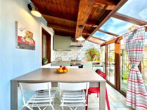 une cuisine avec une table et des chaises avec un bol de fruits dessus dans l'établissement La Corte Azzurra Terrace, à Bari Sardo