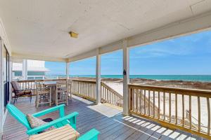 a porch with chairs and a table on the beach at The Beach House in Gulf Shores