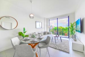 a white living room with a table and a couch at Beautiful and Stylish Condo Close The Doral Park in Miami