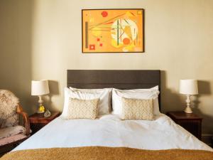 a bedroom with a bed with two lamps and a painting at The Grosvenor Arms in Salisbury