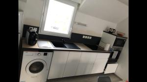 a kitchen with a washing machine and a window at Appartement 2 pièces à Saint René in Hillion