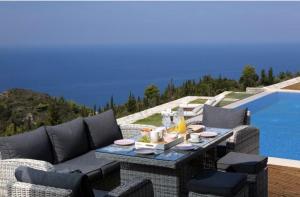 a patio with a table and chairs next to a pool at Pantheon Villas in Agios Nikitas