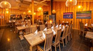 a restaurant with wooden tables and chairs and chandeliers at Aurora Mountain Lodge in Lannavaara
