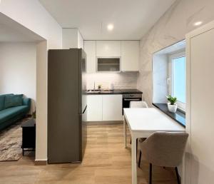 a kitchen and living room with a table and a refrigerator at Casinha PP Guest House in Coimbra