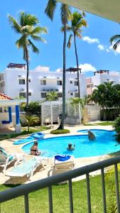 une piscine avec des palmiers et des personnes dans un complexe dans l'établissement The Perfect Place for Holiday in los Corales RD, à Punta Cana
