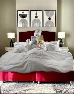 a man laying in bed reading a book at Hotel Fantazia Oradea - Self Check In & Out in Oradea