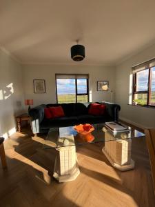 sala de estar con sofá negro y mesa de cristal en Woodview Cottage, en Mill Loughan