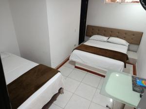 um pequeno quarto com duas camas e uma mesa em Hotel Bayadera Real em Medellín