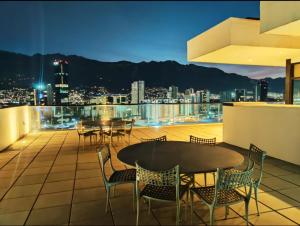 Un balcón con mesas y sillas y un perfil urbano en Departamento con Gran Vista, en Monterrey