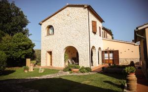 a large stone church with a yard in front of it at Agriturismo La Vecchia Quercia in Montemerano