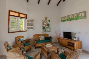 a living room with wicker chairs and a tv at Village Honoré in Saint-François