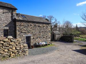 an old stone building with a stone wall at Hardriggs Bank Cottage in Kendal