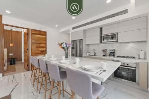 a white kitchen with a long bar with stools at Luxury 2 BR Condo with Dream Pools - Beach - Art in Bucerías
