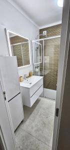 a white bathroom with a sink and a shower at Praia da Rocha in Portimão