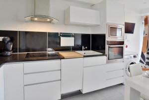 a white kitchen with white cabinets and appliances at Palme Centre ville Terrasse Disneyland 4 personnes avec 1 bébé in Bailly-Romainvilliers