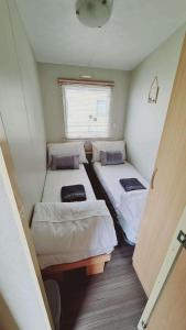 two beds in a small room with a window at 6 Guests - 3 Bedrooms - Entertainment - Near Beach in Sheerness
