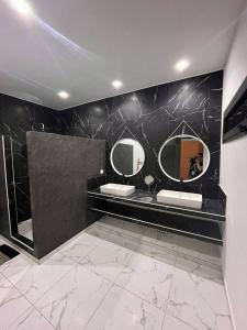 a bathroom with two sinks and two mirrors at Oasis de sérénité in Ngaring