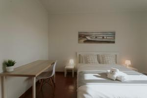 Un dormitorio con dos camas y un escritorio y un cuadro. en Best Houses 115 - Faustino s House II, en Atouguia da Baleia