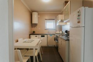 Una pequeña cocina con una mesa y un refrigerador blanco. en Best Houses 115 - Faustino s House II, en Atouguia da Baleia