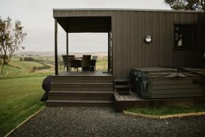 a house with a porch with a table and chairs at Luxury Glamping Cabin sleeping 4 People with Private Hot Tub and BBQ with views across the North Coast Ballycastle Pod 2 in Ballycastle