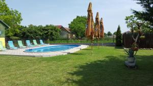basen z leżakami i parasolami na dziedzińcu w obiekcie Pension Hostad w mieście Gabčíkovo
