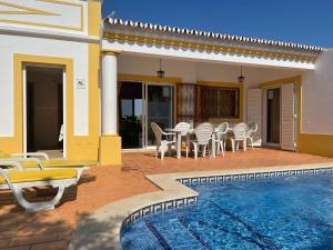 a villa with a pool and chairs and a house at Villa Ana in Albufeira