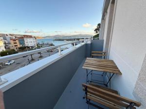 a balcony with a bench and a table on a building at Oktheway Corme in Corme-Puerto