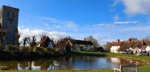 a church with a clock tower next to a river at The Snug in Haddenham