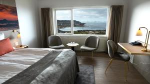 a hotel room with a bed and chairs and a window at Hotel Arctic in Ilulissat