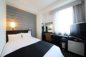 a hotel room with a bed and a flat screen tv at APA Hotel Kagoshima Tenmonkan in Kagoshima