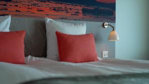 a bedroom with a bed with red pillows and a lamp at Hotel Arctic in Ilulissat